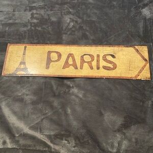 Metal sign that says Paris on it, 1 end has the Eiffel Tower, forward  arrow